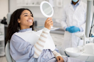 A patient sits in a dentist's chair and admires her teeth