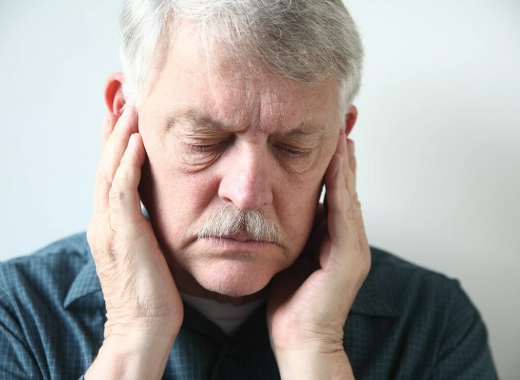 A male holds his head to ease the pain in his jaw